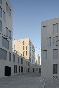 an empty parking lot in front of two buildings with windows on each side and stairs leading up to the second floor