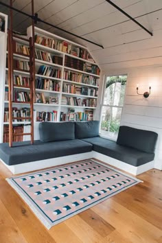 a living room with a couch and bookshelf filled with lots of bookcases