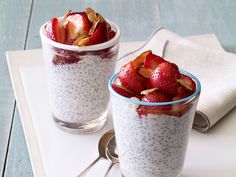 two small cups filled with strawberries on top of a white tray next to each other