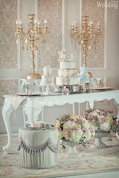 a white table topped with lots of cake and flowers next to a chandelier