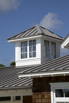 the roof of a house with two windows and a metal shingled dormer on top