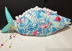 a decorative pillow with flamingos on it and a pin cushion in the shape of a fish