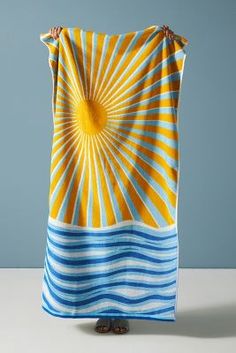 a woman holding up a yellow and blue blanket with sunbursts on it