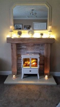 a fireplace with candles lit in front of it and a mirror over the fire place