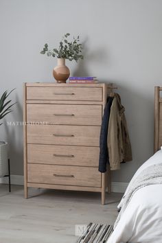 a wooden dresser sitting next to a bed with a plant on it's top