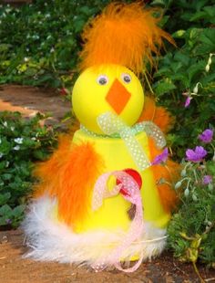 a yellow and orange stuffed animal sitting in front of some bushes with purple flowers behind it