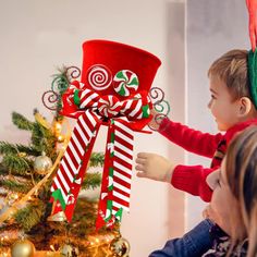 a young boy and girl decorating a christmas tree with candy canes on it