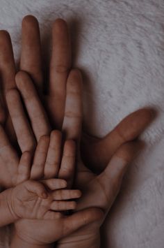 a group of hands that are on top of a white blanket with one hand extended up to the other