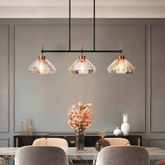 an elegant dining room with gray walls and gold trimmings on the ceiling, along with glass pendant lights