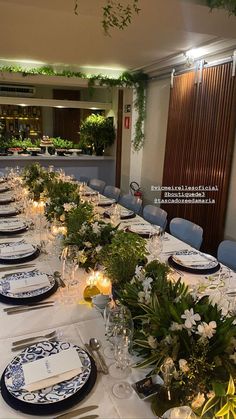 a long table set with blue and white plates, place settings and flowers on it