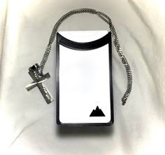 a black and white bag with a cross hanging from it's side on a chain