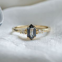 a ring with an emerald stone and three diamond stones on the side, sitting on a white cloth