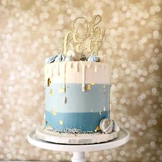 a blue and white cake with gold glitters on the top is sitting on a pedestal