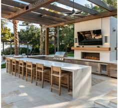 an outdoor kitchen and dining area is shown in this image, with the fireplace visible