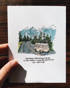 a hand holding up a card with an image of a van driving down the road