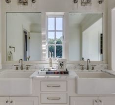 a white kitchen with double sinks and large mirrors