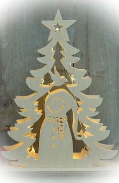 a wooden cutout of a christmas tree with a snowman standing next to it