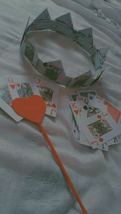 playing cards and a paper heart on a white sheet with a red stick in the middle