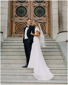 a bride and groom standing in front of a door at the top of some steps