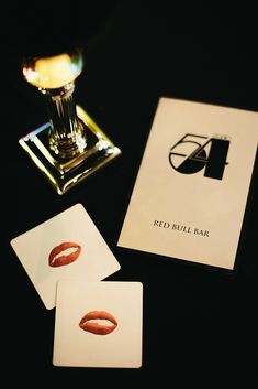 the red bull bar logo and cards are next to a glass of wine on a table