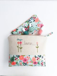 a flowered pouch with personalized name on the front and two pens in it