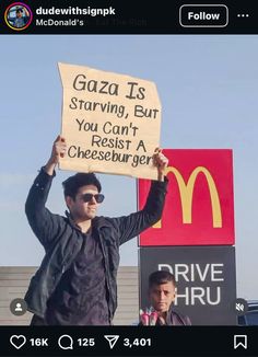 a man holding up a sign in front of a mcdonald's