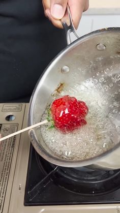 a person is stirring something in a pan with a strawberries on the stove top