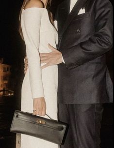 a man in a tuxedo standing next to a woman wearing a white dress