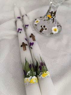 two white candles with crosses and flowers on them