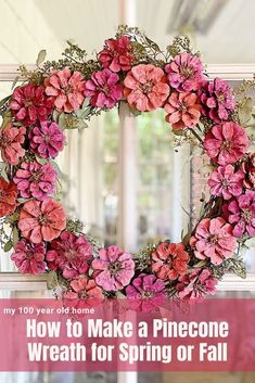 a wreath with pink flowers hanging from the side of a window in front of a door