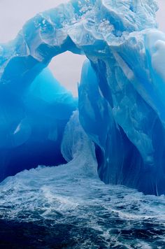 an iceberg in the middle of the ocean with waves coming up from underneath it