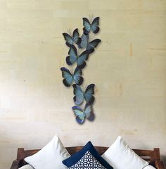 a bed topped with lots of pillows next to a wall mounted butterfly art on the wall