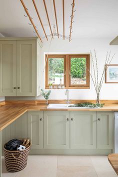 a kitchen with green cabinets and wooden counter tops, along with a basket on the floor