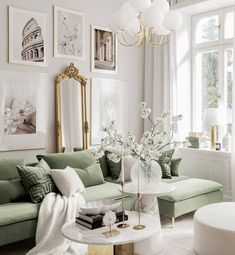 a living room with green couches and pictures on the wall above them, along with a white coffee table