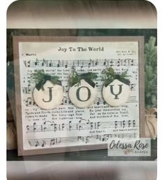 two ornaments are sitting on top of a sheet of music with the words joy to the world