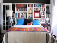 a bed sitting in front of a book shelf filled with books on top of it