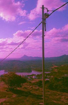 a telephone pole on top of a hill next to a lake