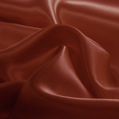 a close up view of a red satin fabric with very soft folds and smooth lines