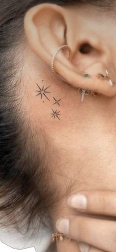 a close up of a person's ear with small stars on the back of their left ear