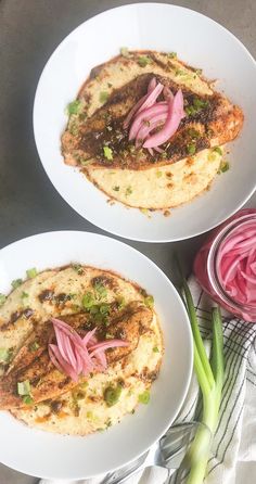 two white plates filled with food on top of a table next to onions and celery