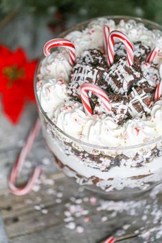 a dessert with white frosting and candy canes in a glass bowl on a wooden table