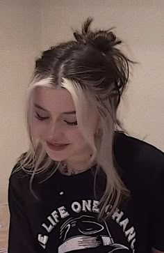 a woman with long hair wearing a black shirt and looking down at her cell phone