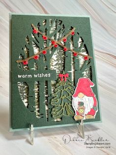 a christmas card with trees and gnomes on it, which says warm wishes in the middle