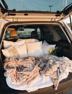 the back end of a car with blankets and pillows in the cargo area on top of it