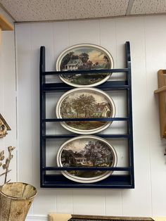 three plates are hanging on the wall above a shelf with other plates and pans