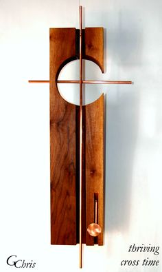 a wooden cross hanging from the side of a wall next to a clock on a white wall