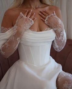 a woman in a white wedding dress with long gloves on her chest and arms over her shoulder