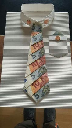 a tie made out of money sitting on top of a table next to a person's feet