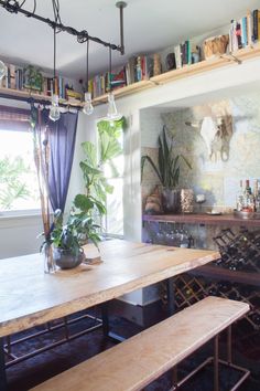 a dining room table with benches and bookshelves on the wall in front of it