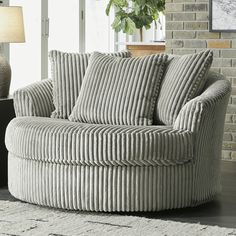 a living room with a round couch and lamp on the side table in front of a brick wall